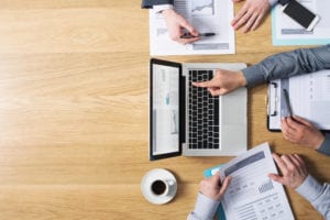 overhead shot of three people looking through financial information