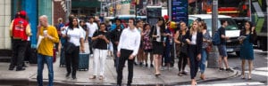 busy group of people on the sidewalk at a city intersection